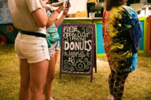 three women standing beside signage on grass field